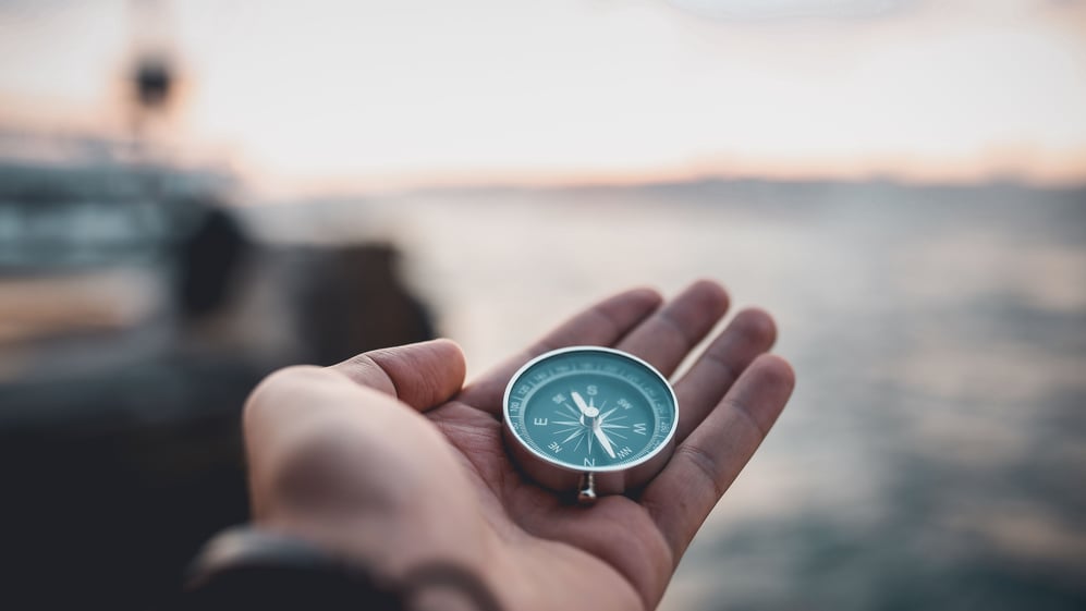 Person holding compass in hand overlooking ocean