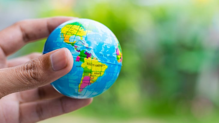 Person holding small globe looking at North, Central, and South America