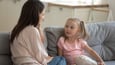 Woman sits on couch with young daughter
