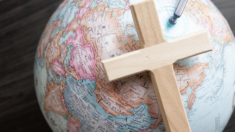Wooden Christian cross sitting on globe