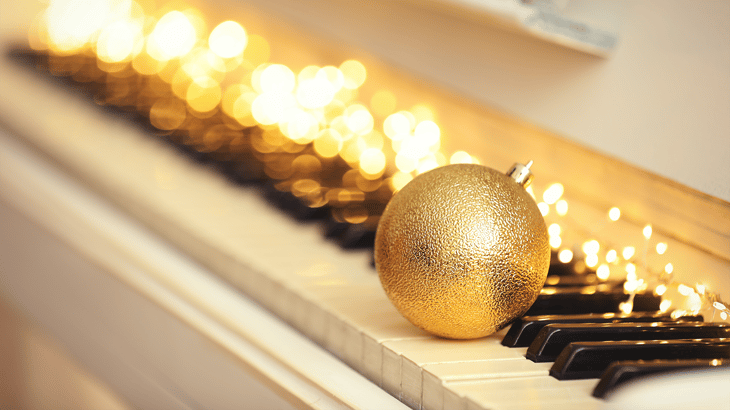 A golden ornament sits on a piano with lights