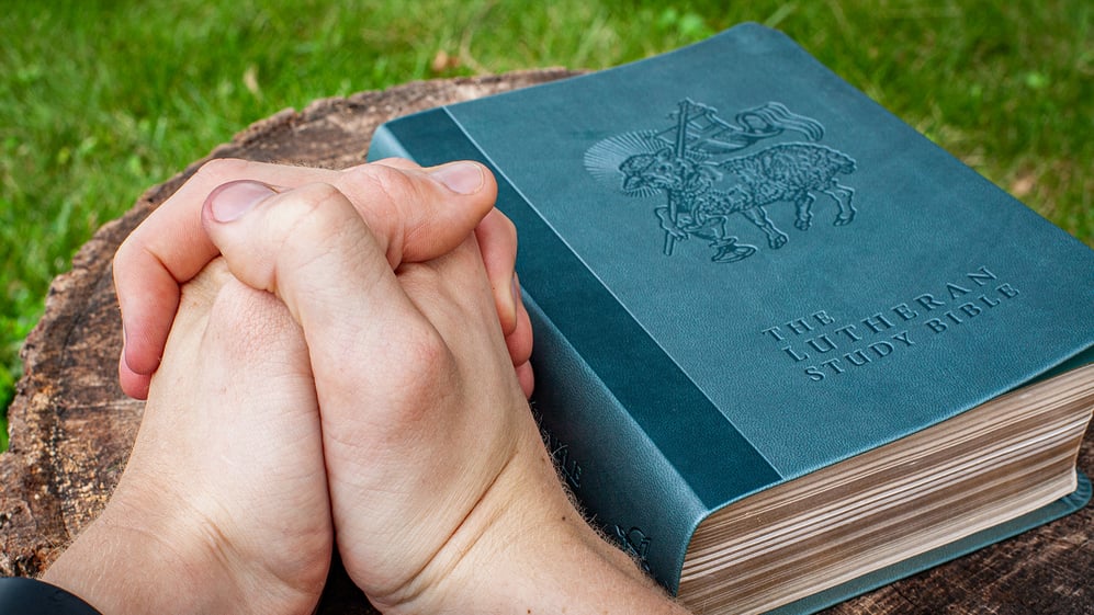 Praying hands with the Bible and Ten Treasures of Learning to Pray
