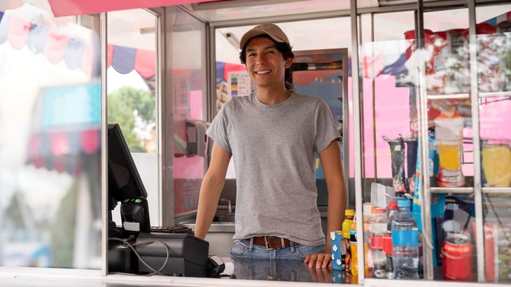 Image:  A man stands at the register in a carnival cart 
