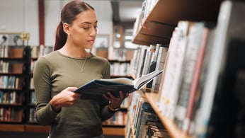 Woman looks at book at library