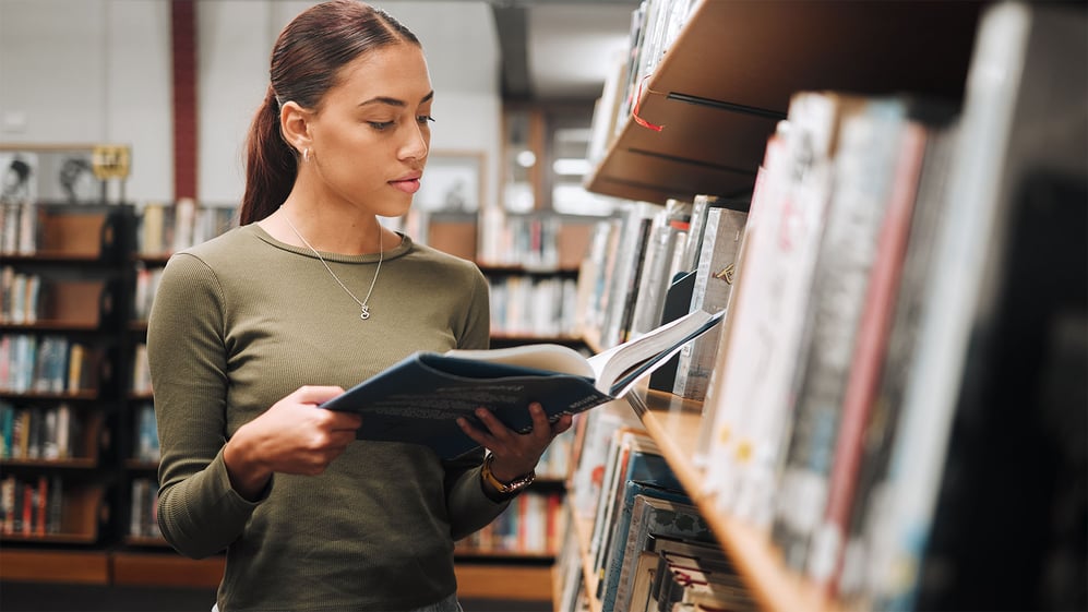 Woman looks at book at library