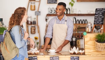 Male barista helps young woman at café