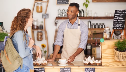 Male barista helps young woman at café