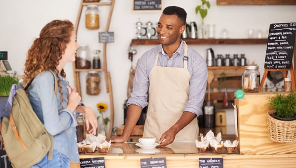 Male barista helps young woman at café