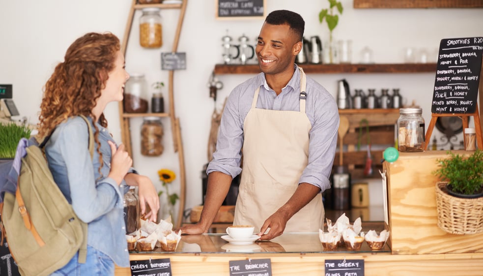 Male barista helps young woman at café