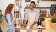 Male barista helps young woman at café