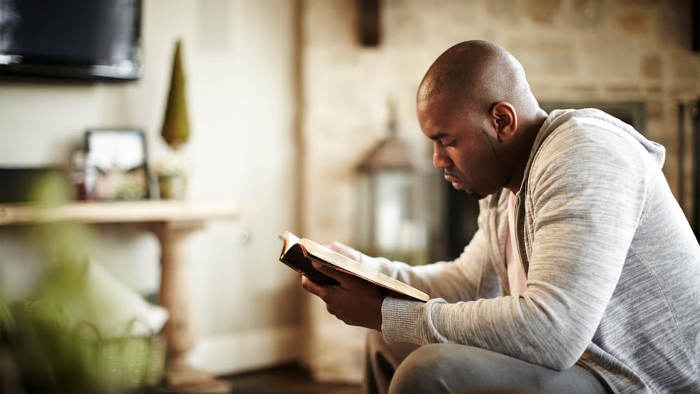 man reading bible in his home
