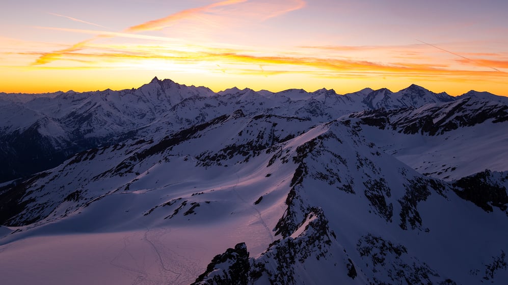 Snow-covered mountains with sun setting