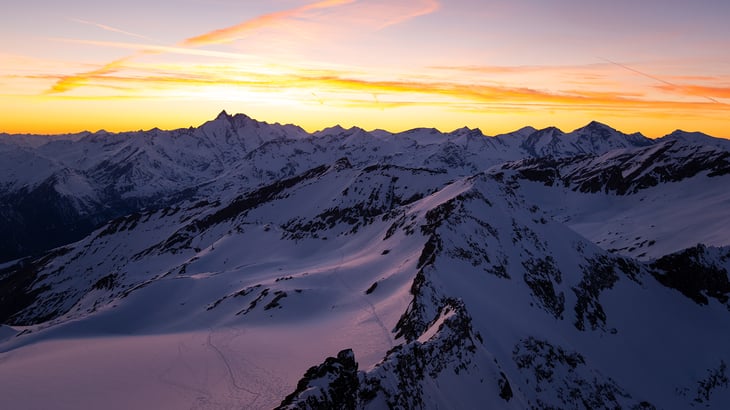 Snow-covered mountains with sun setting