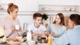 Family is sitting at a table together in discussion during meal time. Son is speaking.