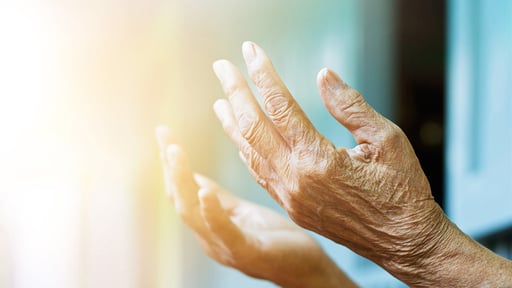 The outstretched hands of an older person in prayer.