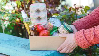 Woman holds a box of canned goods and groceries from a food pantry