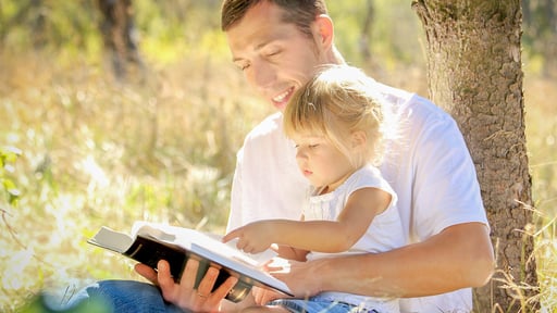 Father and young daughter read the Bible together