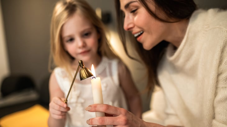 Mother and daughter light candle in remembrance of Baptism