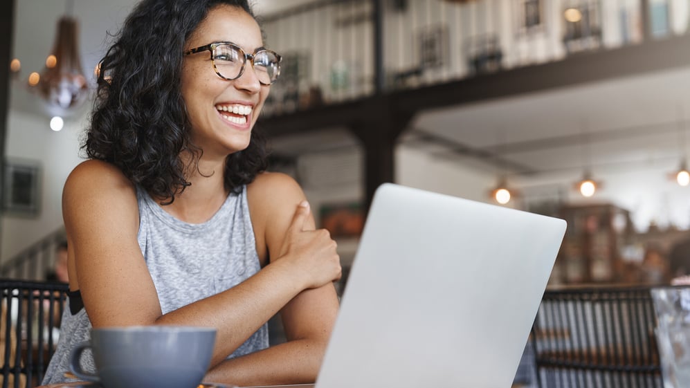 Woman sits with her laptop smiling