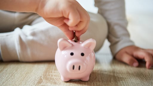 Child putting coin in piggy bank