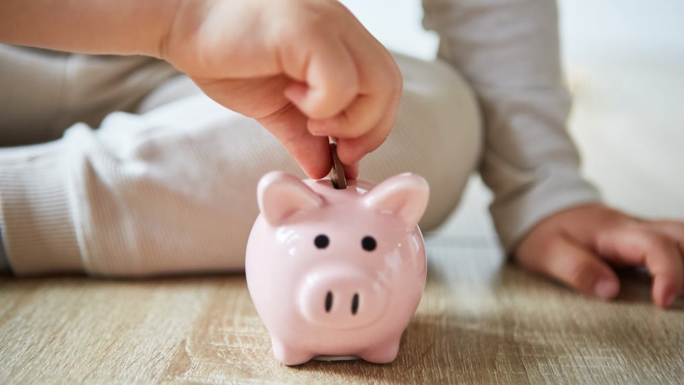 Child putting coin in piggy bank