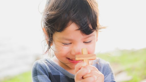 Child embracing a wooden cross