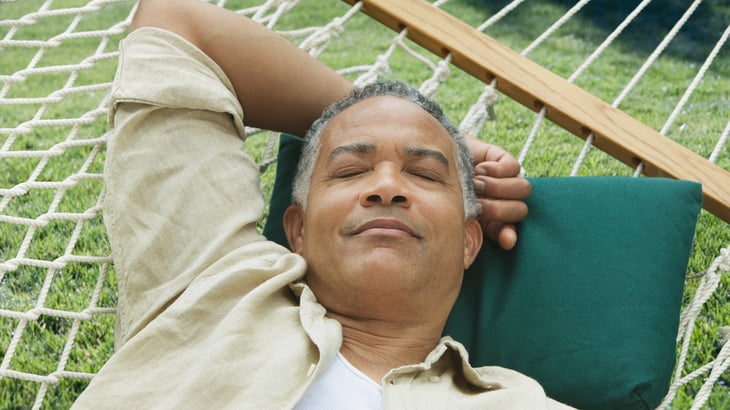 Image of a man lounging on a hammock in the summer. 