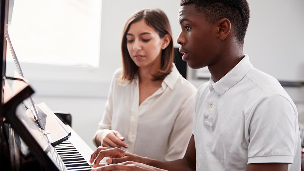 A piano teacher helping a student 