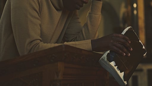repenting man holds Bible in church sanctuary