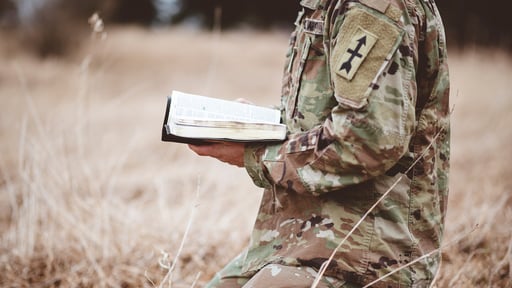 Military serviceman kneeling with Bible