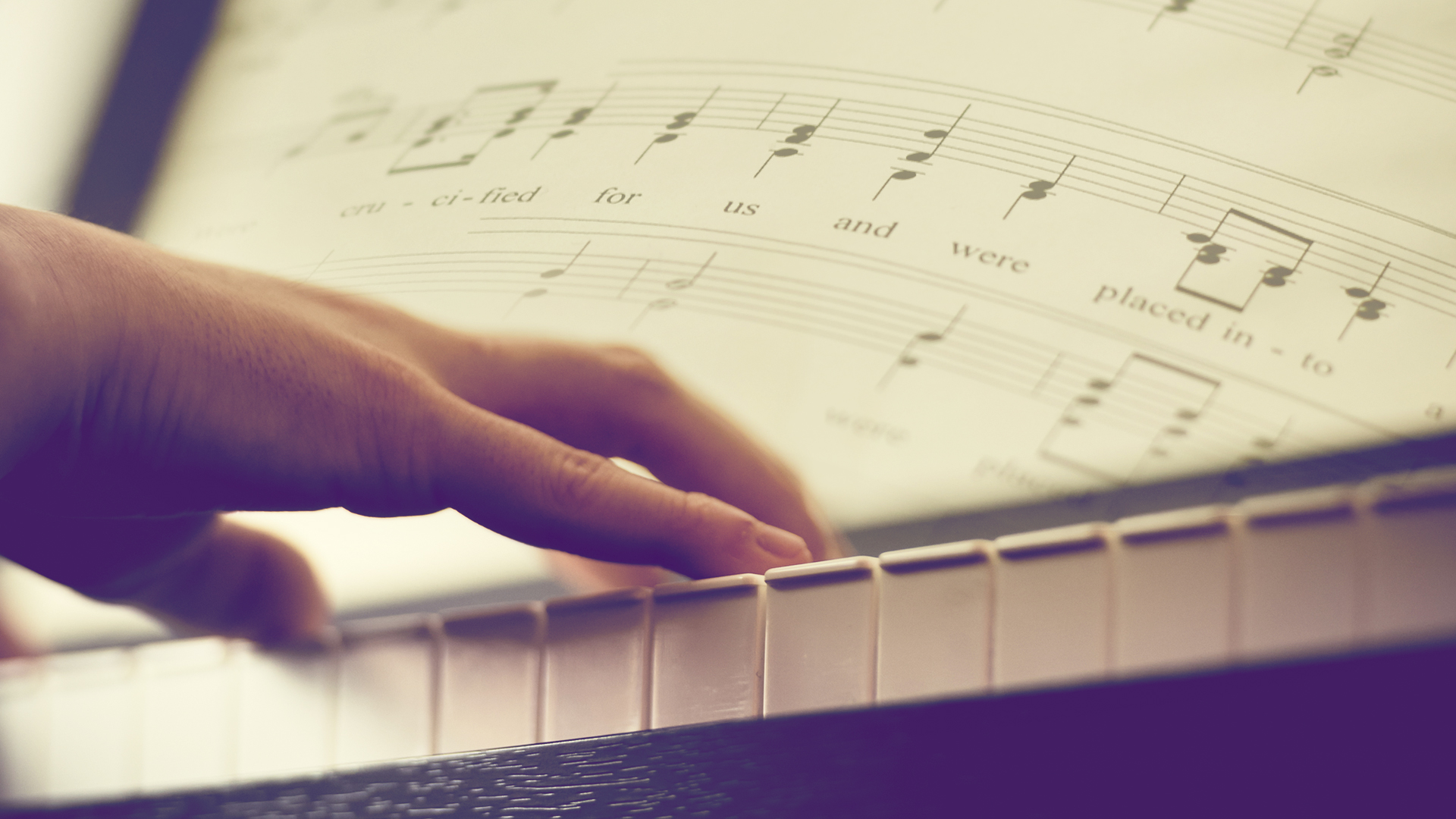 hand-playing-piano-with-sheet-music-transposed-over-photograph